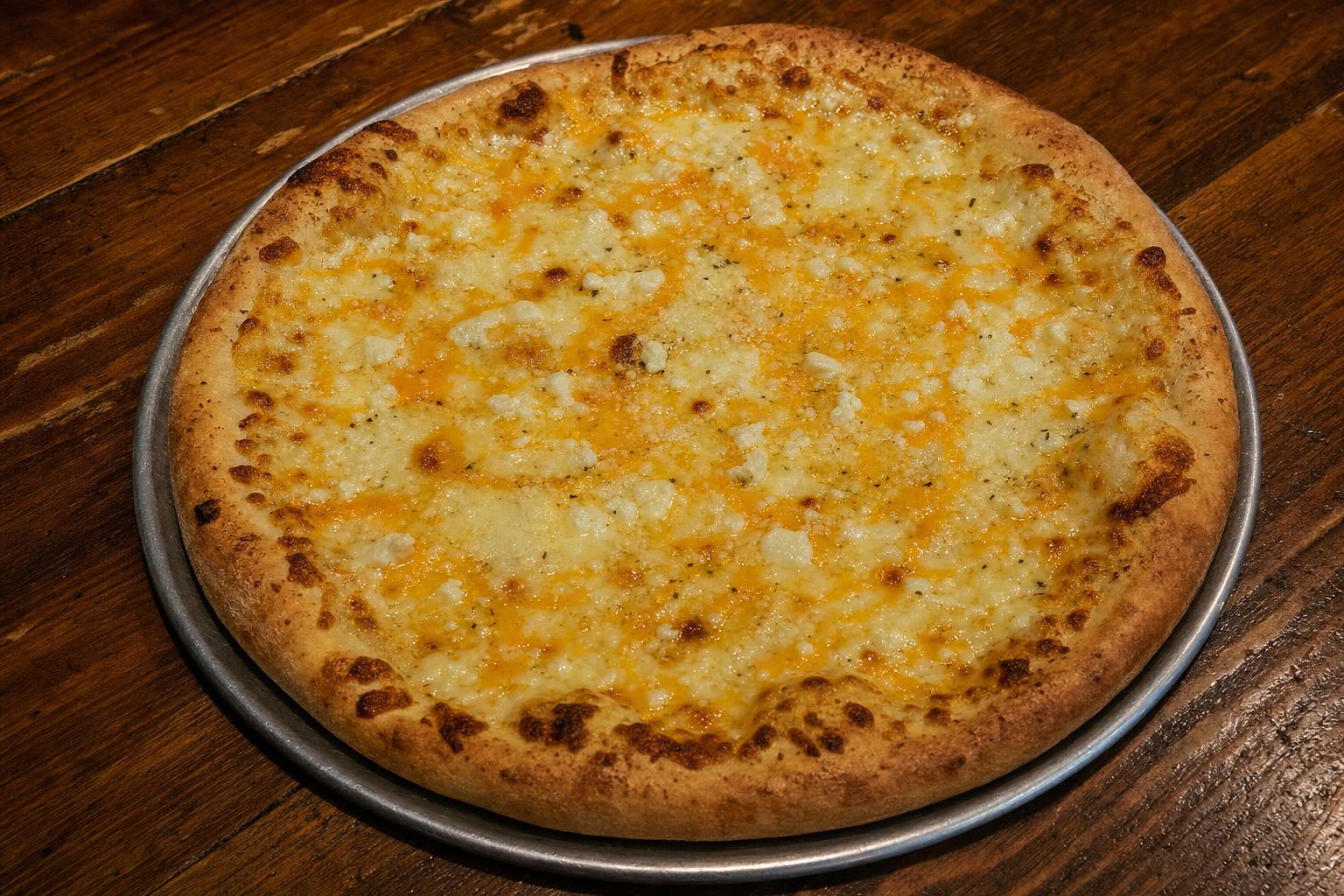 Five Cheese pizza with garlic butter sauce, mozzarella, cheddar and monterey jack blend, parmesan, and feta on a warm wood table.