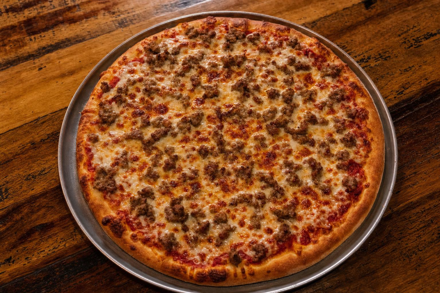 Ground Sausage pizza with pizza sauce, mozzarella cheese, and ground italian sausage on a warm wood table.