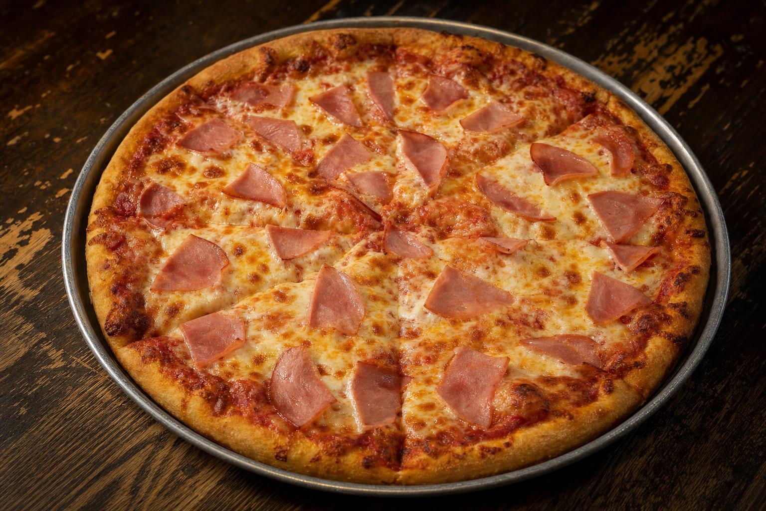 Ham pizza with pizza sauce, mozzarella cheese, and ham on a warm wood table.