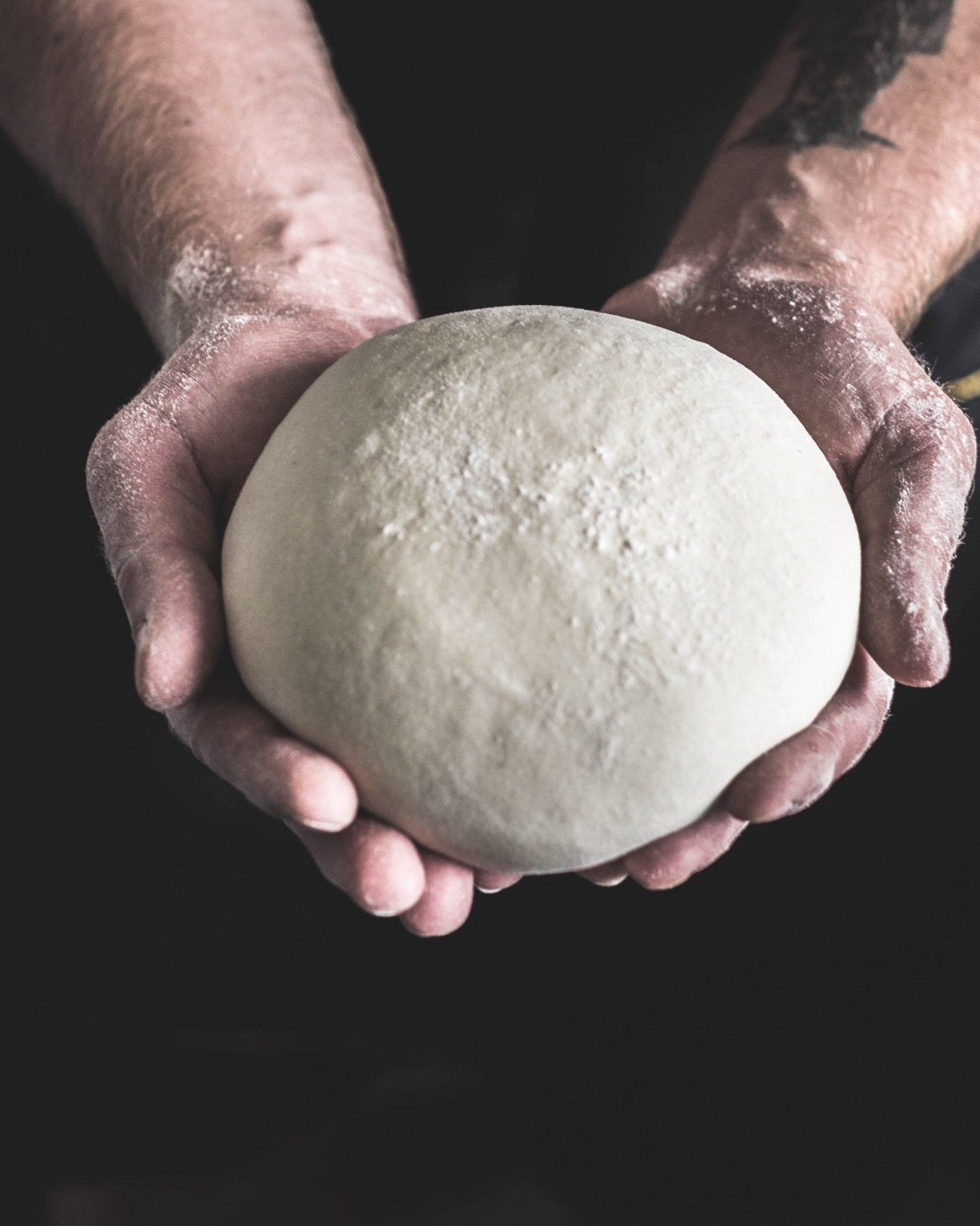 Hands rolling fresh pizza dough on flour
