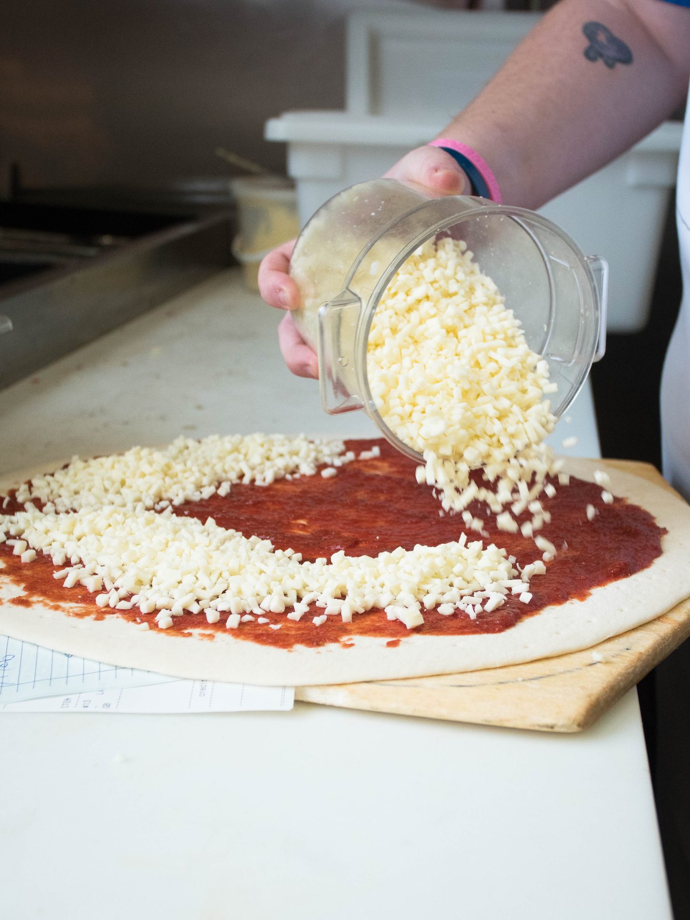 Shredded mozzarella poured over fresh sauce