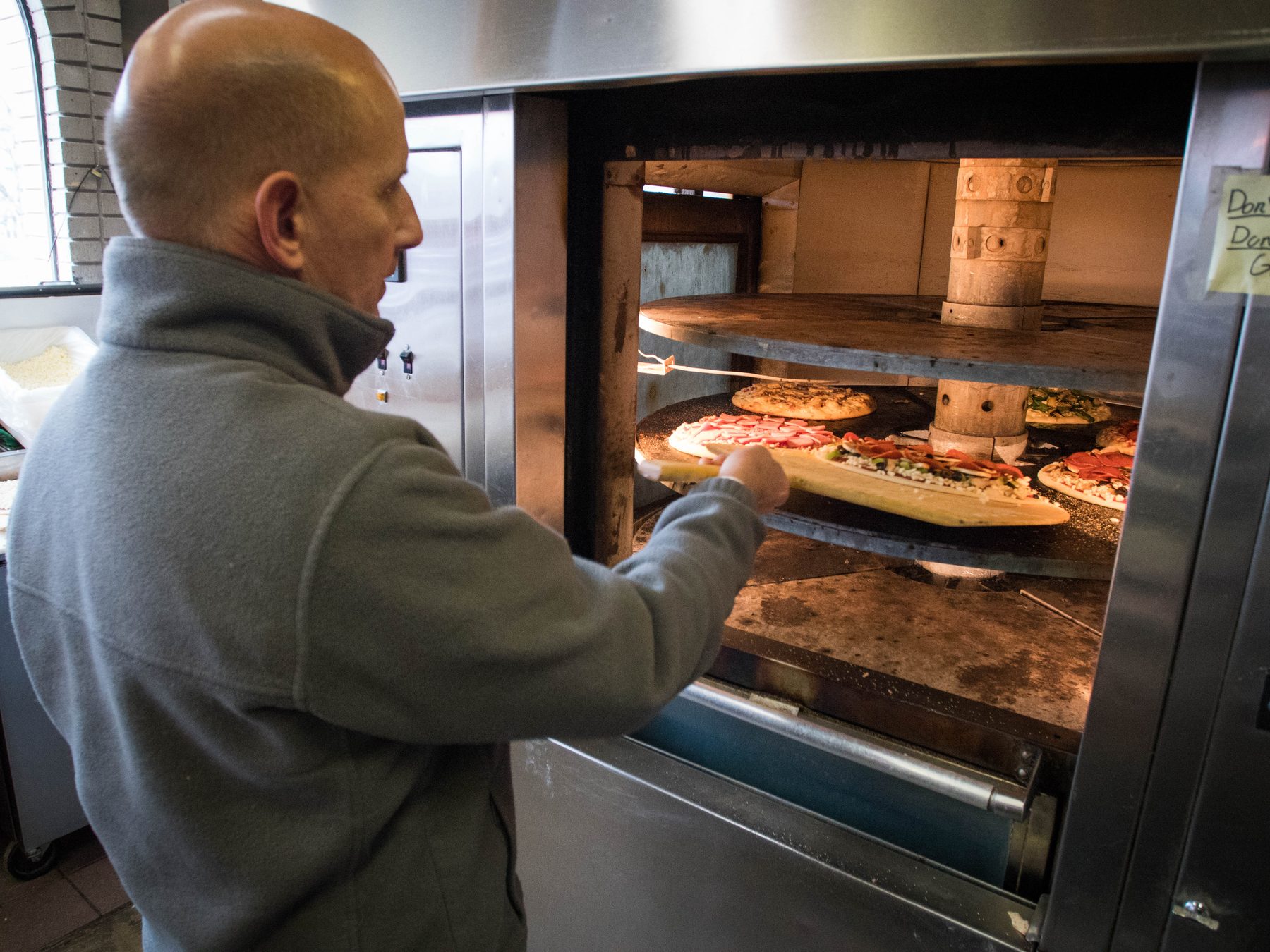 The owner sliding pizzas into the rotating deck oven