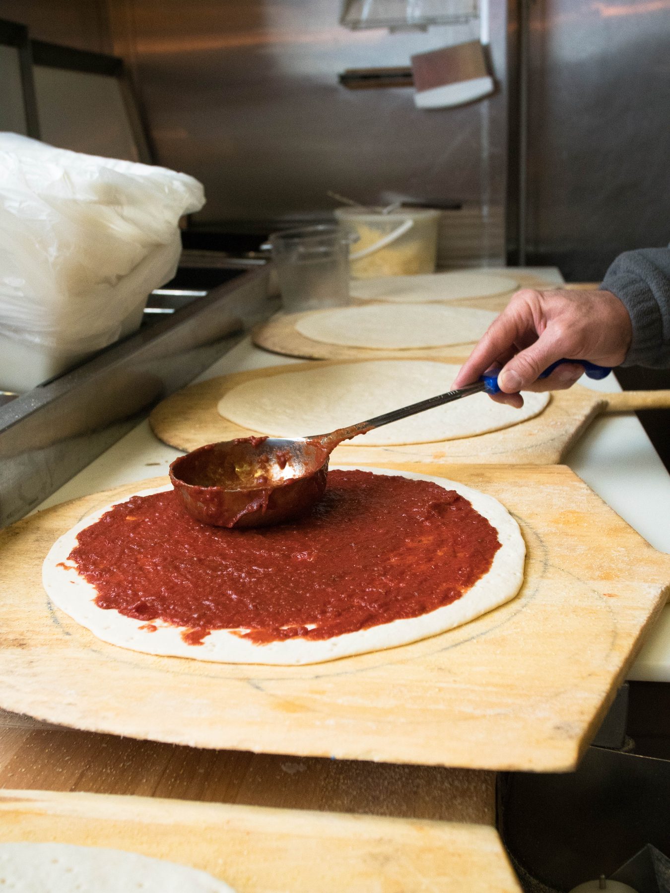 Ladling sauce onto hand-rolled dough